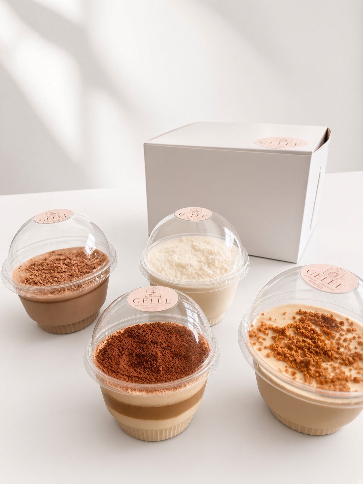 Los cuatro sabores de GELÉE en vaso individual junto a la caja de la marca